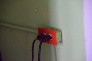 an electric outlet with a red covering to denote it's powered by a solar microgrid