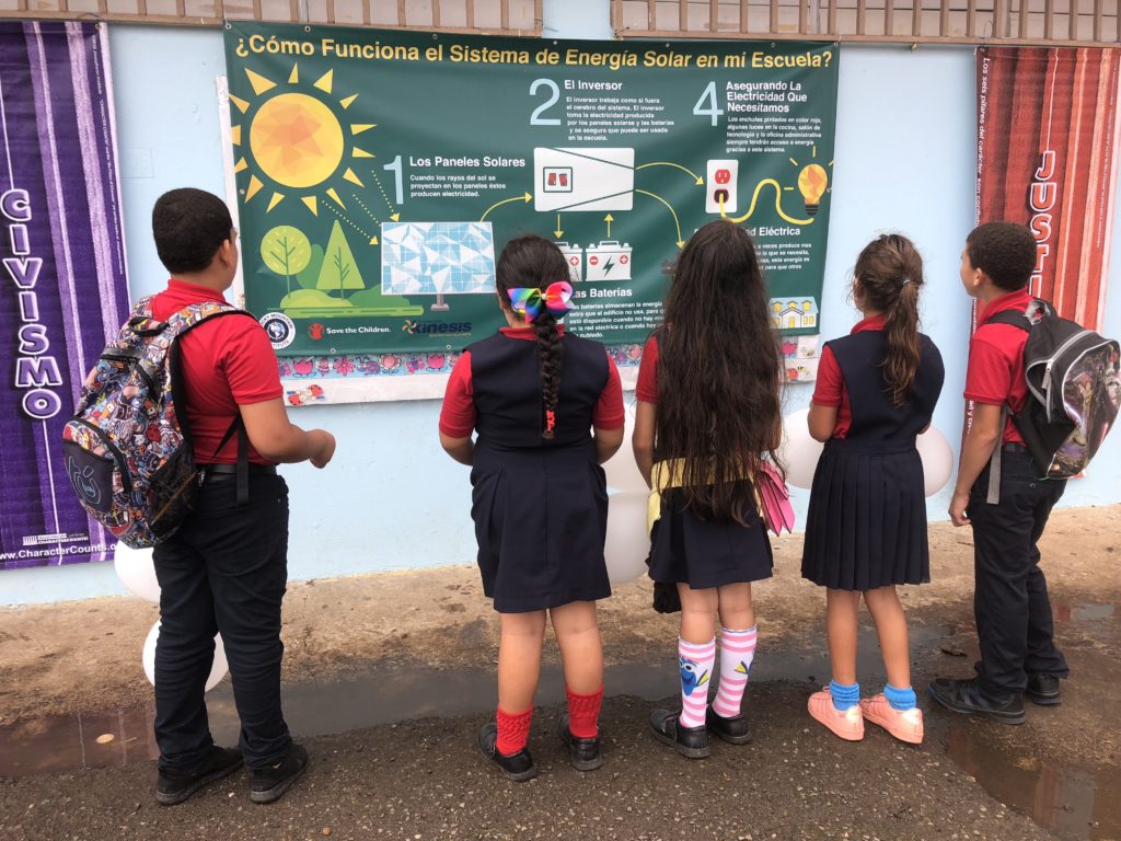 School children in Puerto Rico reading a poster about solar microgrids